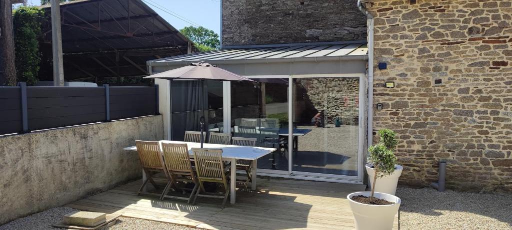 a table and chairs with an umbrella on a patio at Gîte L'hôtellerie in Trévron