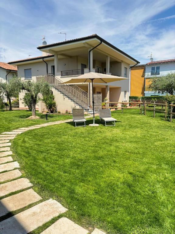 a house with two chairs and an umbrella in a yard at Arlu lake house Lazise in Lazise