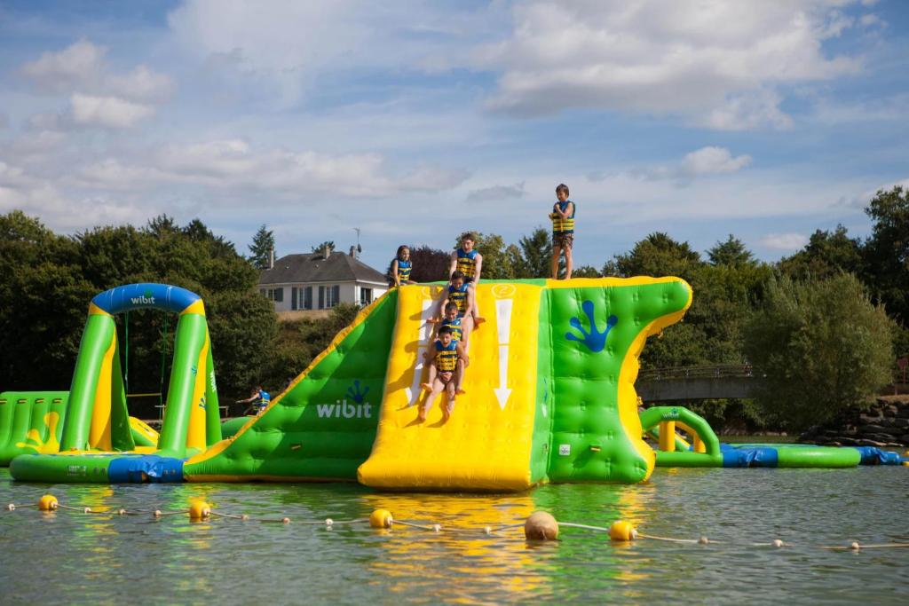 a water slide in the water with people standing on it at Camping 3 étoiles - ccbfige in Pouancé