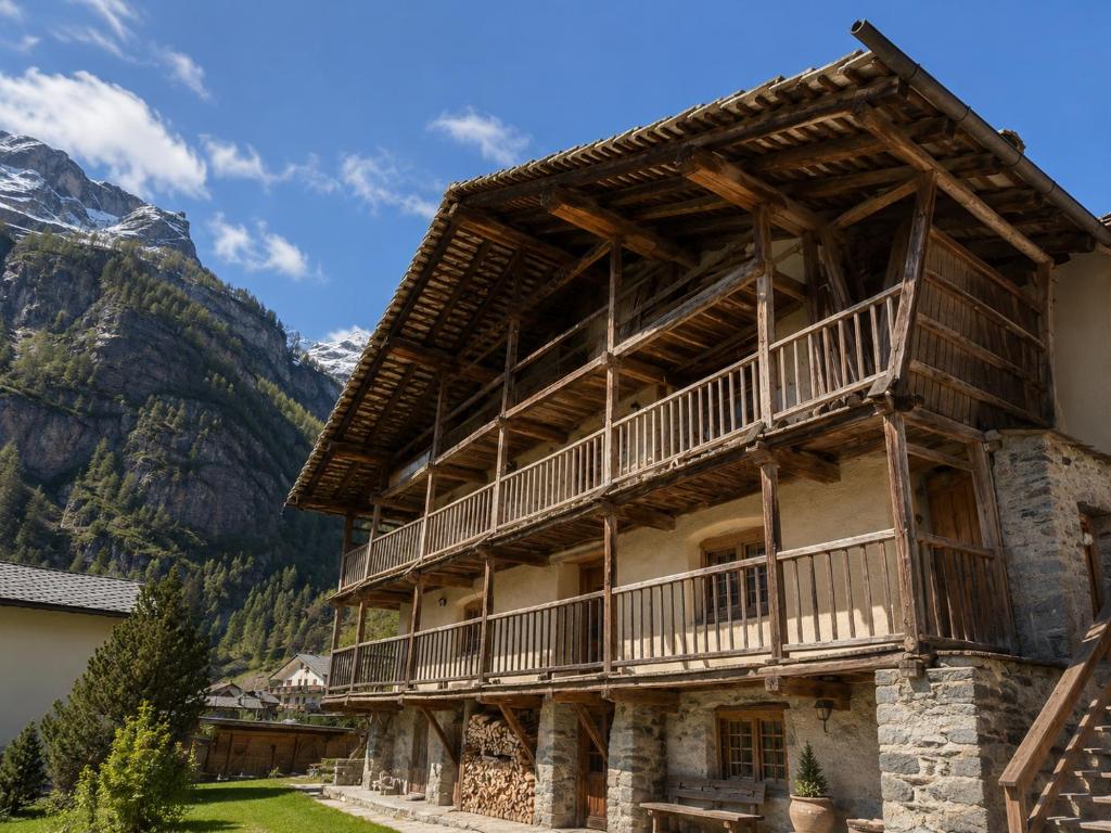 a building with a balcony and mountains in the background at Casalpina Cozy chalet in Gressoney-la-Trinité