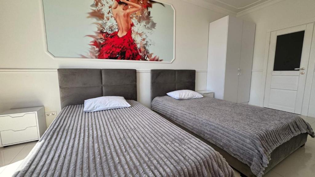 two beds in a bedroom with a painting on the wall at Sun apartments in Kyiv