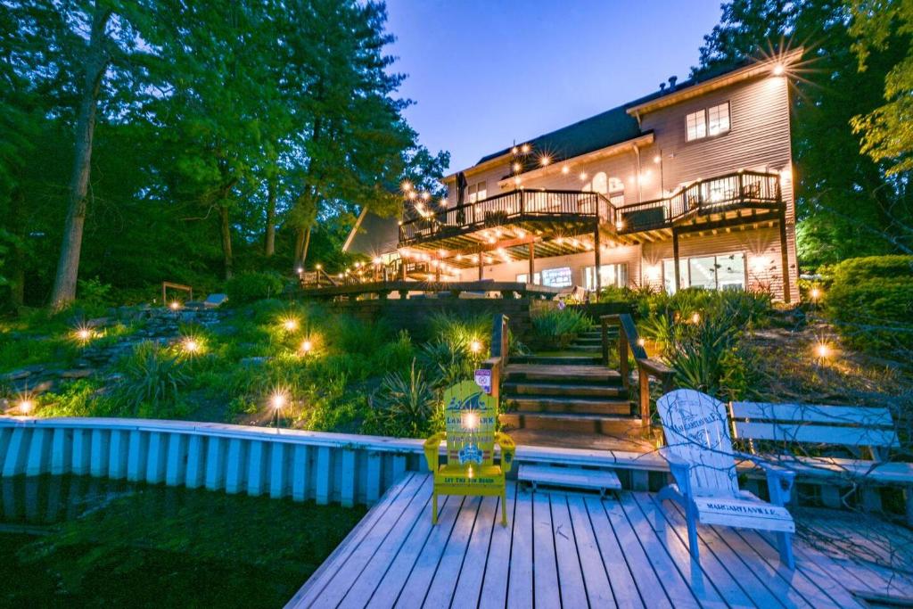 a house with a deck with two chairs and lights at Lakefront Group Stay, Sleeps 19, Indoor Pool, Hot Tub, Arcades in Terre Haute