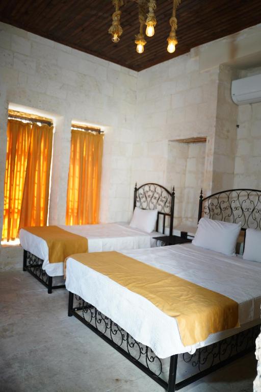 two beds in a bedroom with orange curtains at Hızmalı OTEL in Urfa
