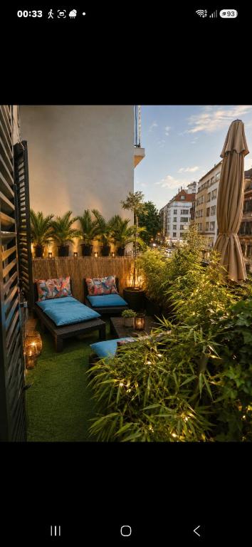 a patio with two blue couches and a umbrella at La Terrasse Desaix in Strasbourg