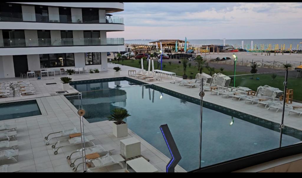 a swimming pool with white chairs and a building at Eva Del Mar 1, vedere la mare-parcare gratuita in Mamaia