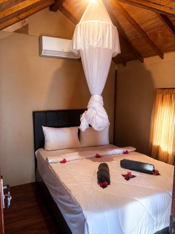 a bed with some flowers on top of it at El-Mindri Bungalow dan Resto in Gili Gede