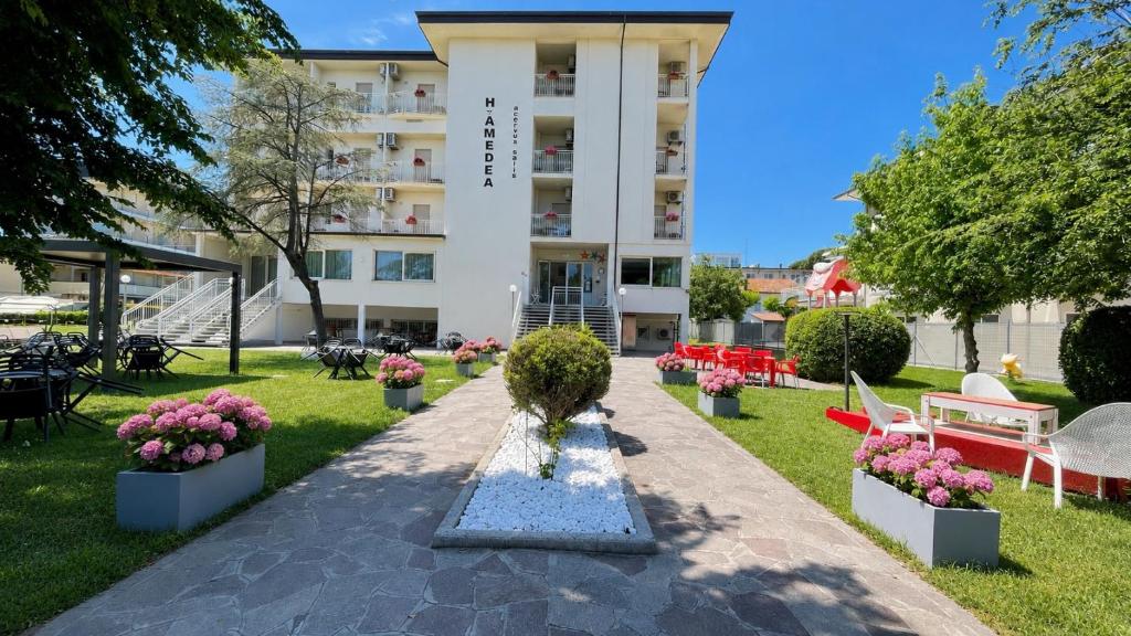un parque frente a un edificio con flores y una fuente en Hotel Amedea, en Cervia