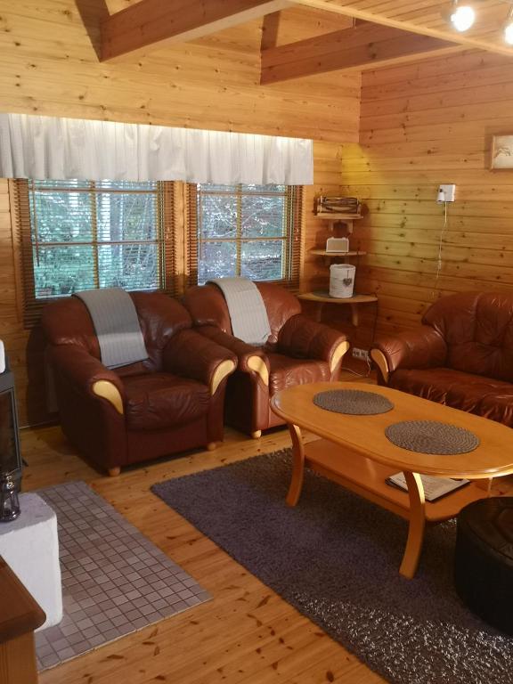 a living room with leather couches and a table at Talvitahko 3 in Nilsiä