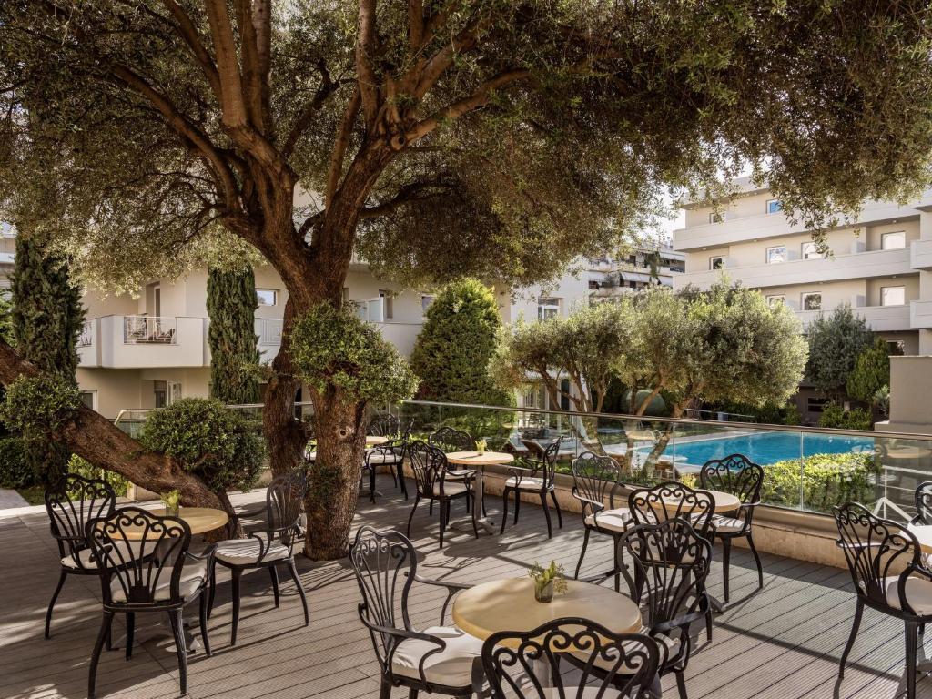 an outdoor patio with tables and chairs and a tree at Civitel Attik Rooms & Suites in Athens