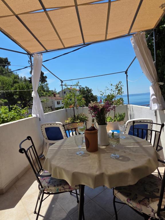 a table on a balcony with a view of the ocean at Mala Cele in Podgora