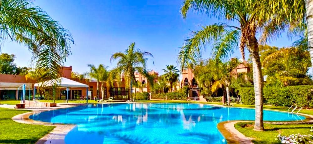 a swimming pool with palm trees in a yard at villa Marrakech 3chambre in Marrakesh