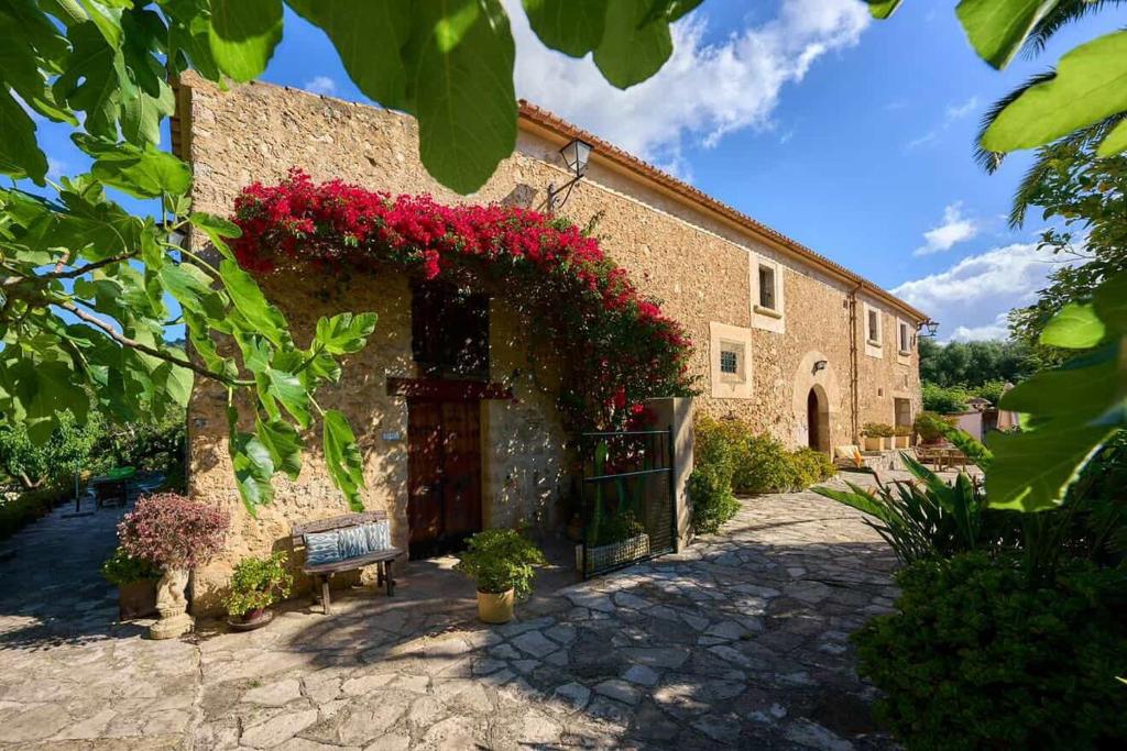 a brick building with red flowers on it at Agroturismo Can Guillo in Pollença