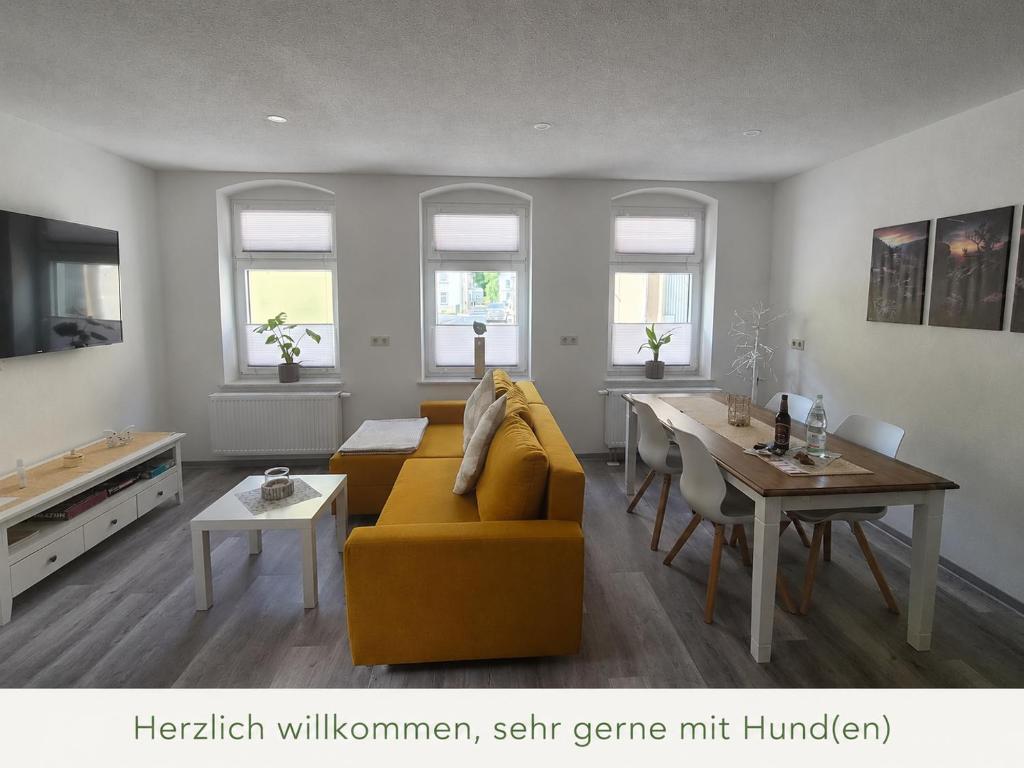 a living room with a yellow couch and a table at FeWo Herzenstölen in Sebnitz