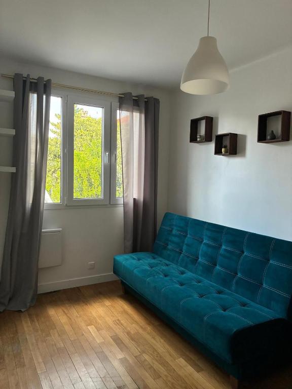 a blue couch in a room with a window at Studio 4 in Arcueil