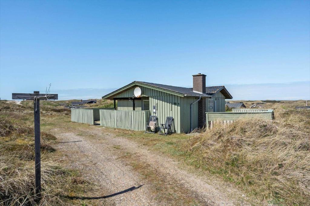 a green building on a dirt road next to a dirt road at 5514-Hvide-Sande-Riskrogvej-18-C in Havrvig