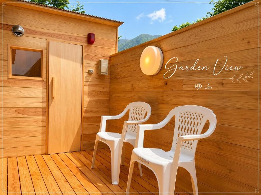 two white chairs sitting on a wooden deck at Garden-View ゆふ in Yufu