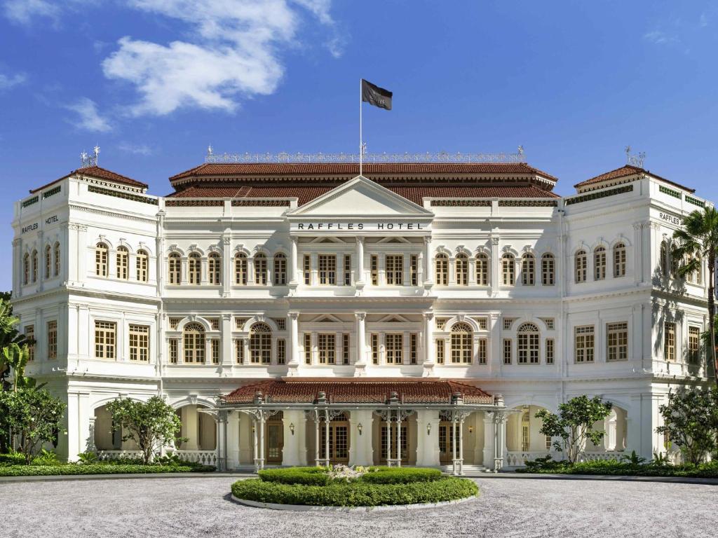 a large white building with a flag on top at Raffles Singapore in Singapore