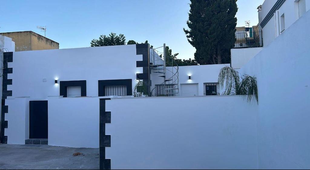 a row of white buildings with trees in the background at Apartamentos Canoa centro y playa in Sanlúcar de Barrameda