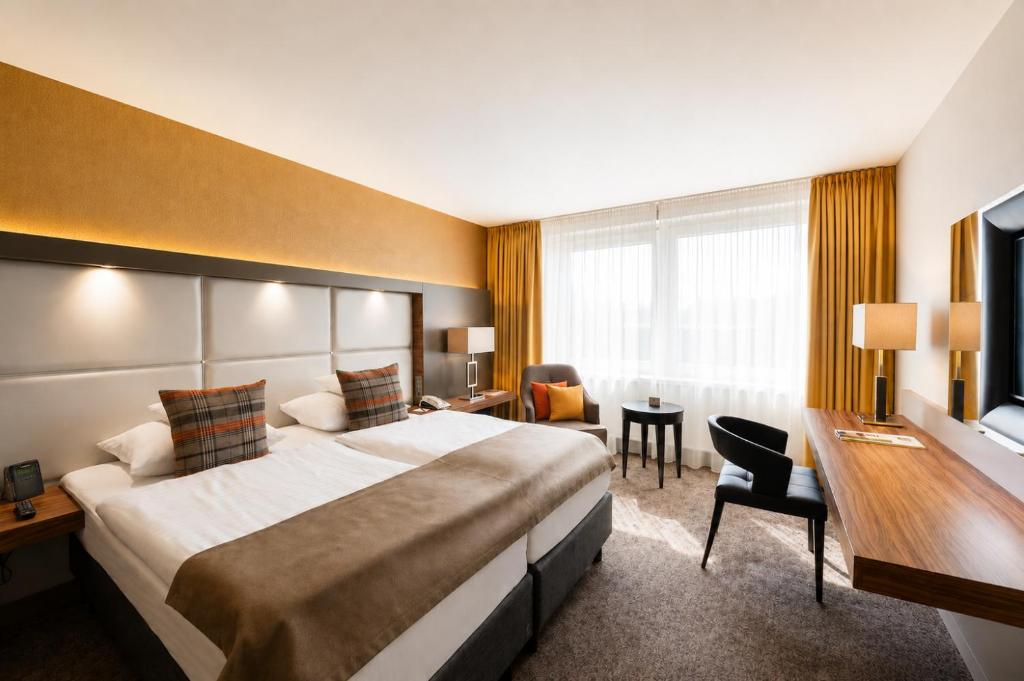 a hotel room with a large bed and a desk at Best Western Plus Delta Park Hotel in Mannheim