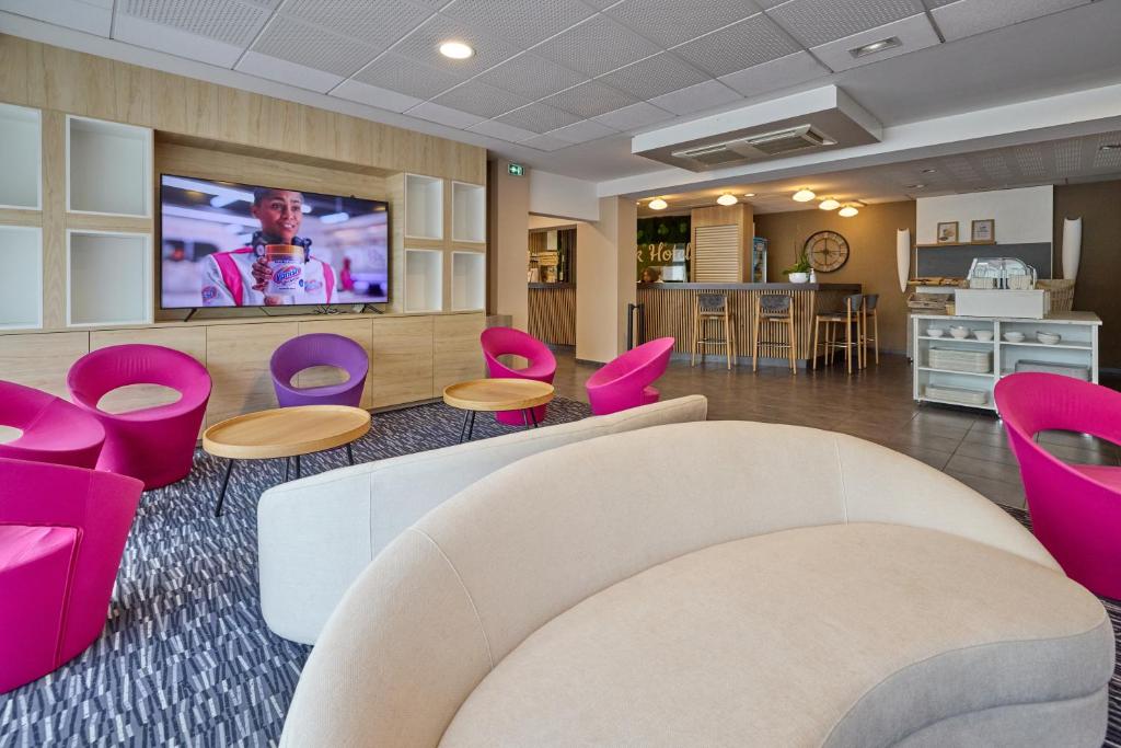 a waiting room with pink chairs and a flat screen tv at Park Hôtel & Appartements in Cholet