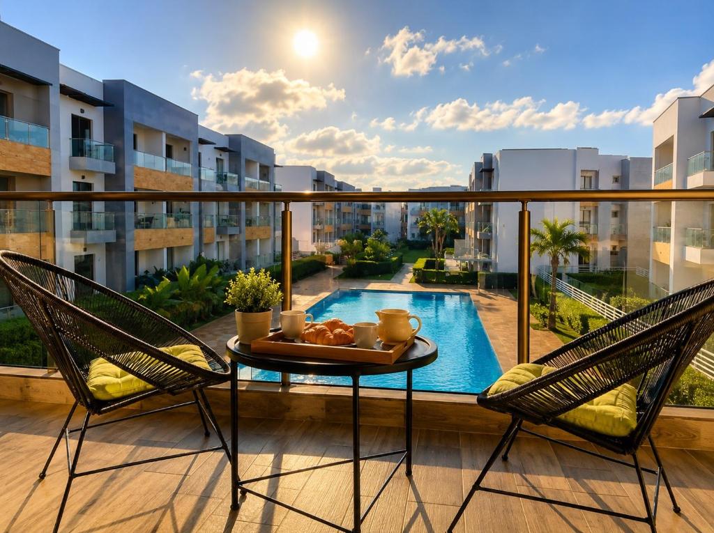 a balcony with a table and two chairs and a pool at Sunny Apartment with Pool View & Terrace in Casablanca