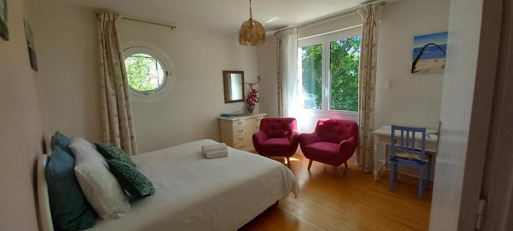 a bedroom with a bed and two red chairs at Villa Do Sol Chambre d'Hôtes "Les Pins" in Arcachon