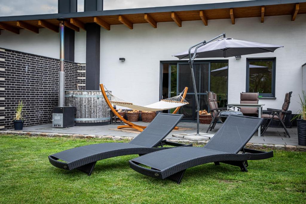 two chairs and an umbrella on the grass at Familienfreundliche Ferienwohnung mit großem Garten, Spielplatz, privatem Badefass & Sauna in Wendisch Rietz