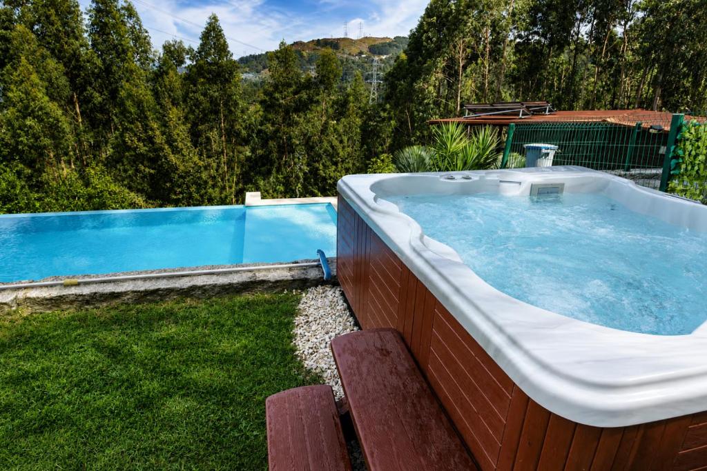 a large bath tub sitting next to a swimming pool at Recanto do Escalheiro in Vieira do Minho