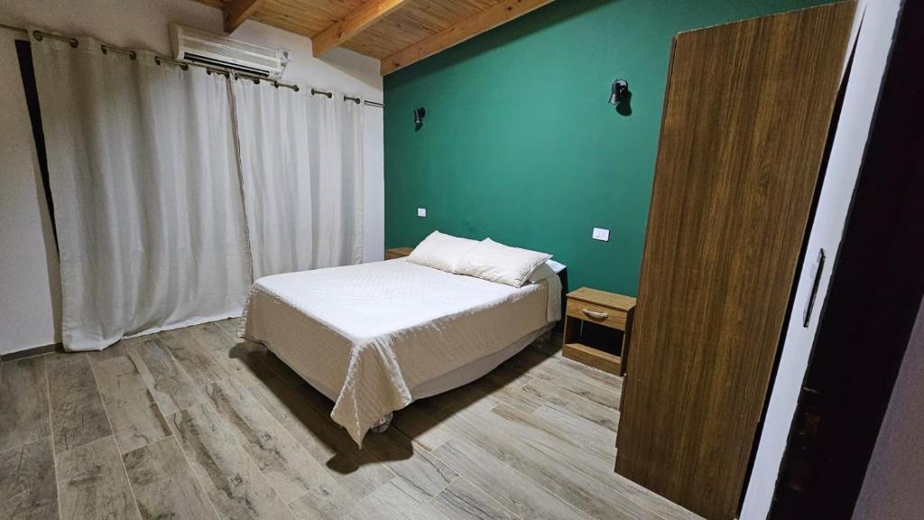a bedroom with a bed and a green wall at Azahares Apart in Bella Vista