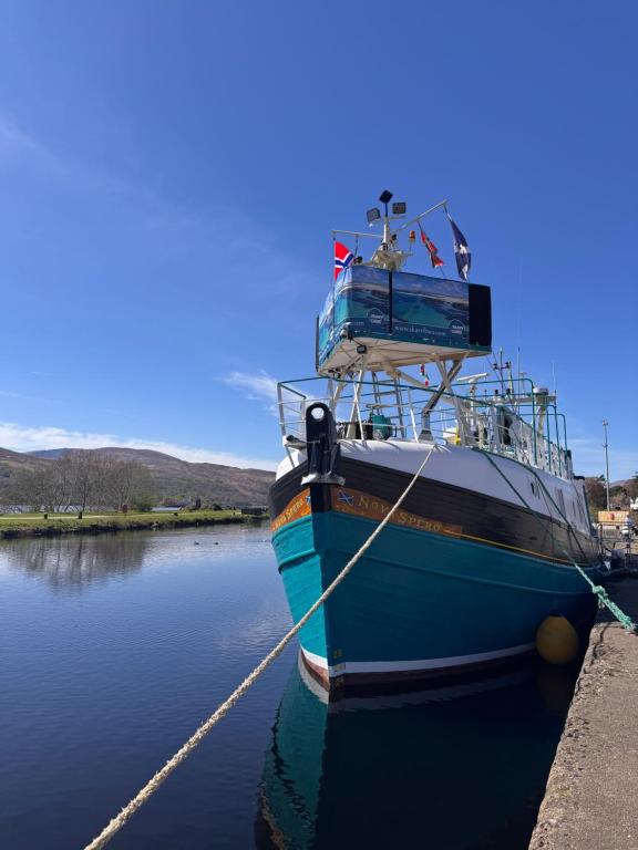 a blue boat tied to a dock in the water at Nova Spero Boat & Breakfast - Caledonian Canal in Fort William