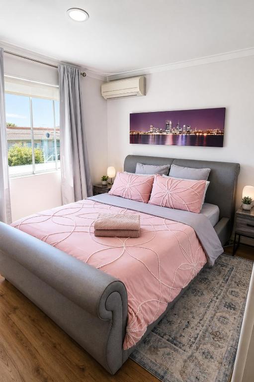 a bedroom with a large bed with pink sheets at Modern Unit Near CBD & Beach, Free Parking in Perth