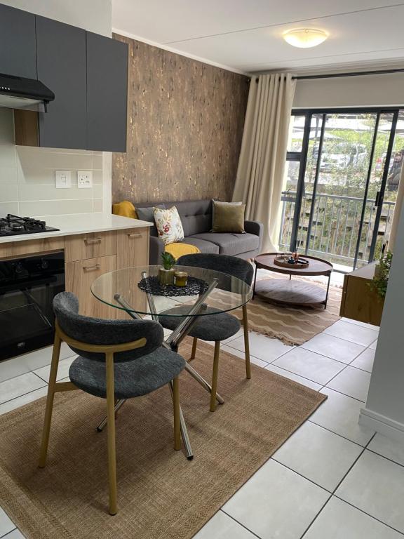 a kitchen and living room with a glass table and chairs at EdenNest in Boksburg