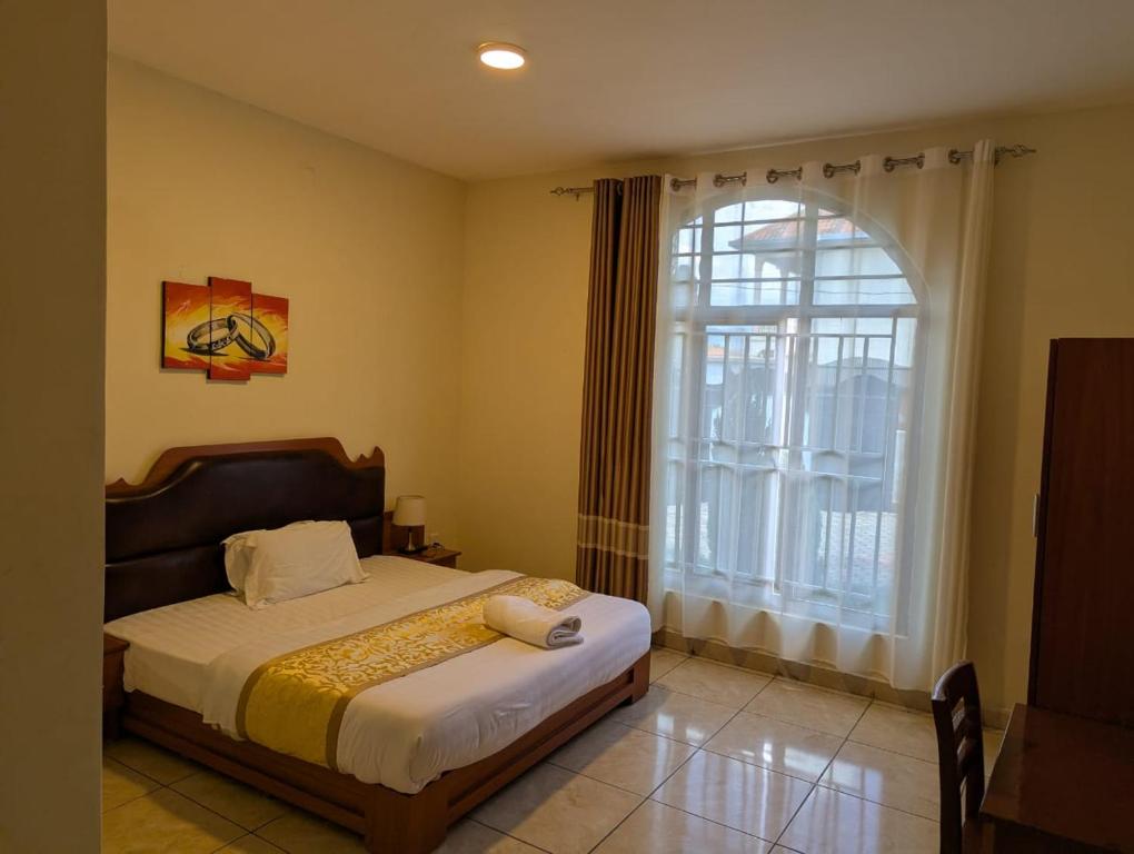 a bedroom with a bed and a large window at Gorilla Trekking Guest House in Ruhengeri