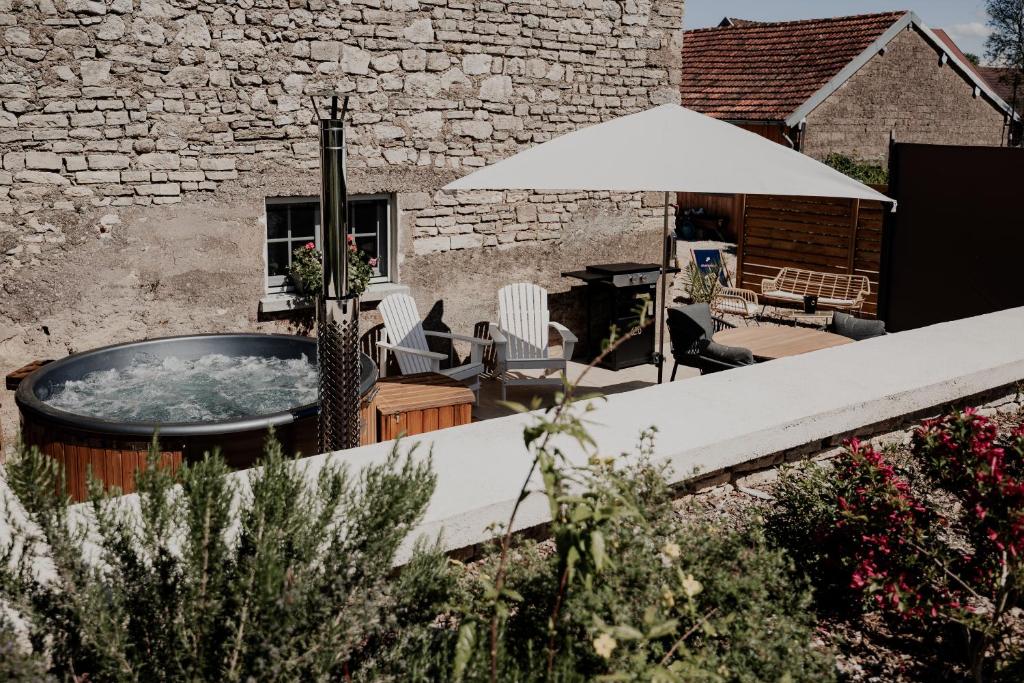 a patio with a hot tub and chairs and an umbrella at Gite L étable du Bien Etre in Ray-sur-Saône