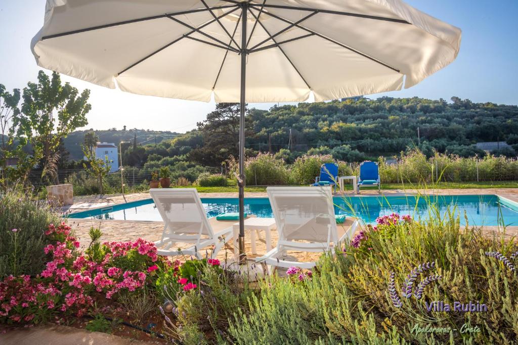 a pair of chairs and an umbrella next to a swimming pool at Villa Rubin in Almyrida