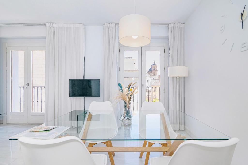a dining room with a glass table and white chairs at Apartamentos Domus con parking gratuito in Granada