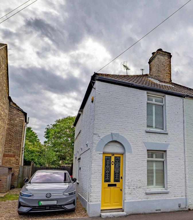 a car parked next to a white house with a yellow door at Seagrass Cottage - 3bed, Private Parking, Secluded Garden, Minutes from Whitstable town in Whitstable