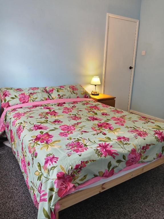 a bedroom with a bed with a floral bedspread at Double Bed in Sawston
