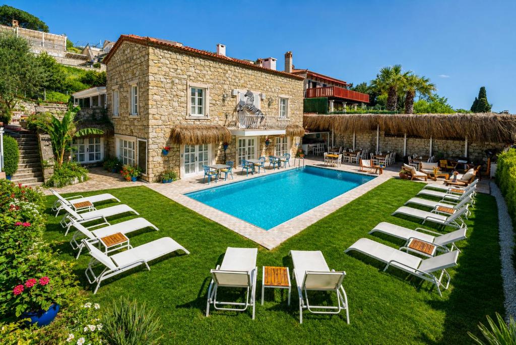 a villa with a swimming pool and lounge chairs at ALAÇATI ROKA TAŞ BUTİK HOTEL in Çeşme