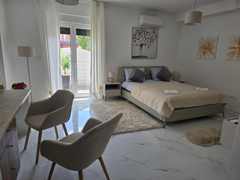 a bedroom with a bed and two chairs in it at Studio apartman Carera Deluxe in Vinkovci