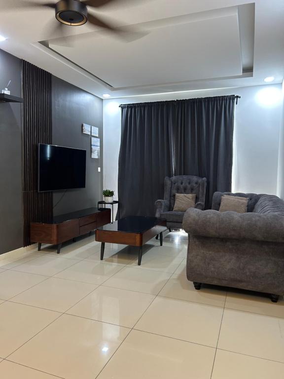 a living room with couches and a flat screen tv at Sunset Retreat Sensory Residence in Kampung Dengkil