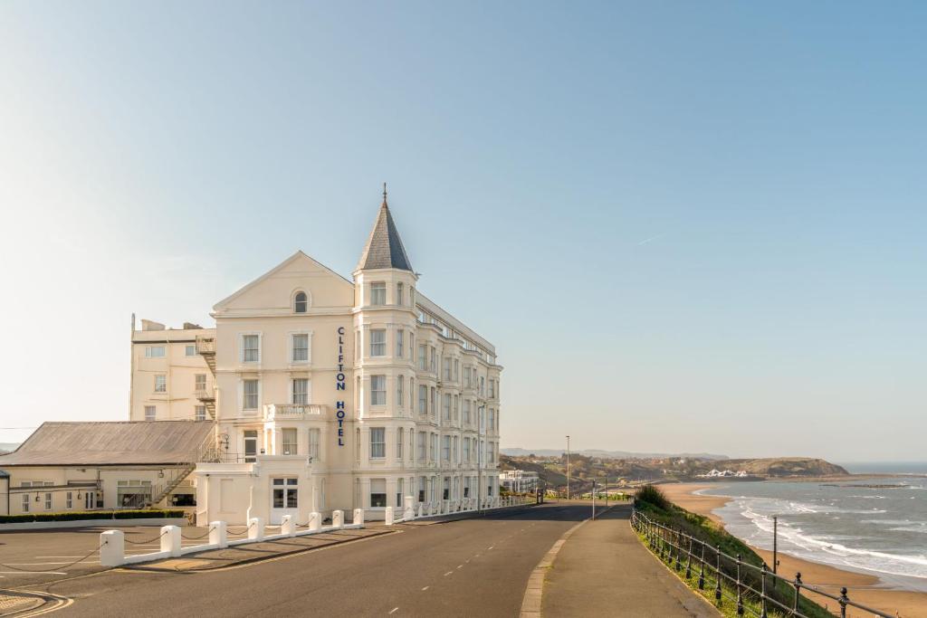 a white building on the beach next to the ocean at Clifton Hotel in Scarborough