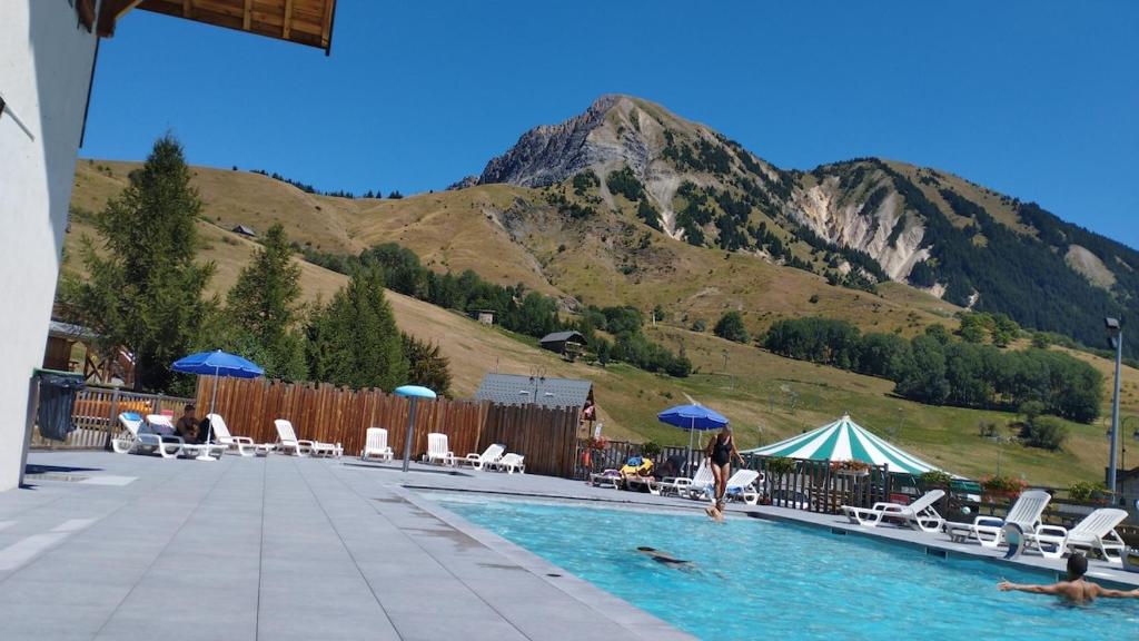 a woman in a swimming pool with a mountain in the background at Studio plein sud avec piscine in Saint-Jean-dʼArves