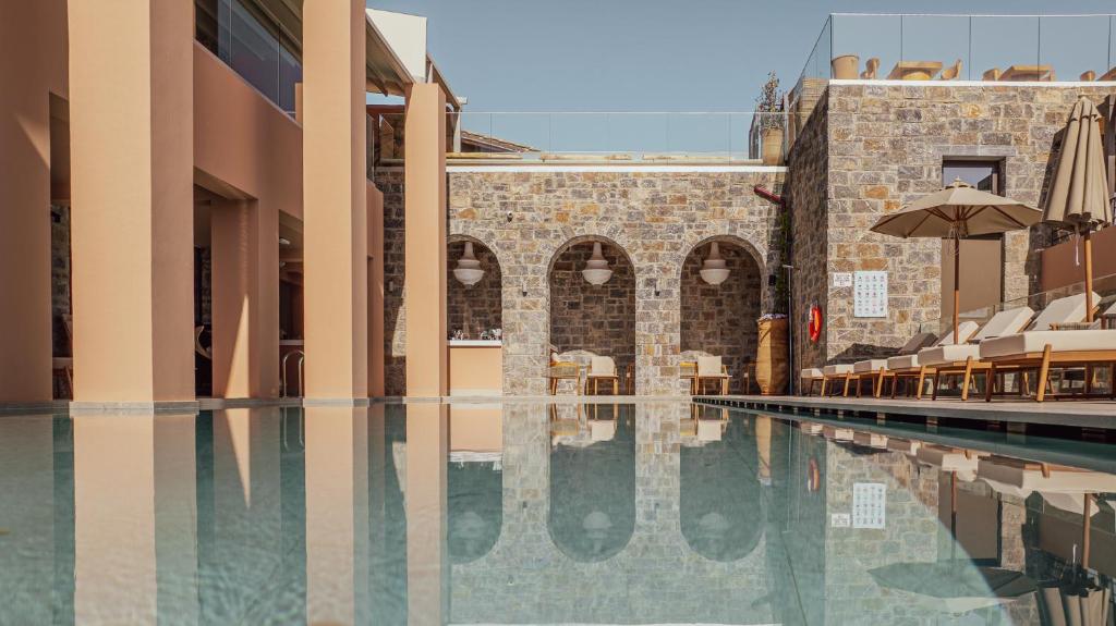 an empty swimming pool in a building with an umbrella at Volta Seaside Boutique Hotel in Kokkini Khanion