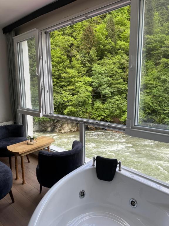 a bath tub in a room with a large window at Pine Suit in Çamlıhemşin