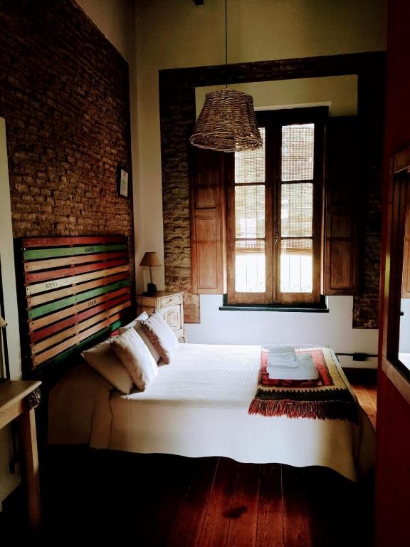 a bedroom with a large white bed and two windows at Hostería Casa de Campo in Chascomús