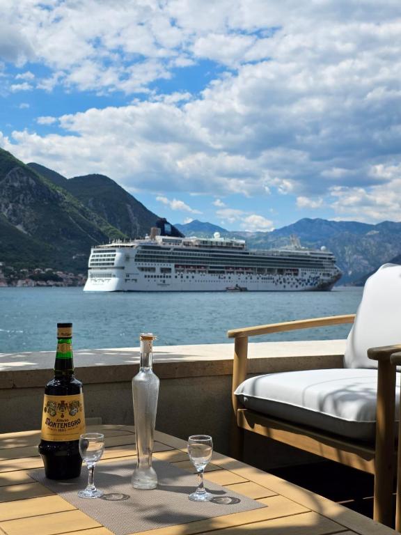 a bottle of wine and glasses on a table with a cruise ship at Studio Lanterna in a seaside house in Dobrota