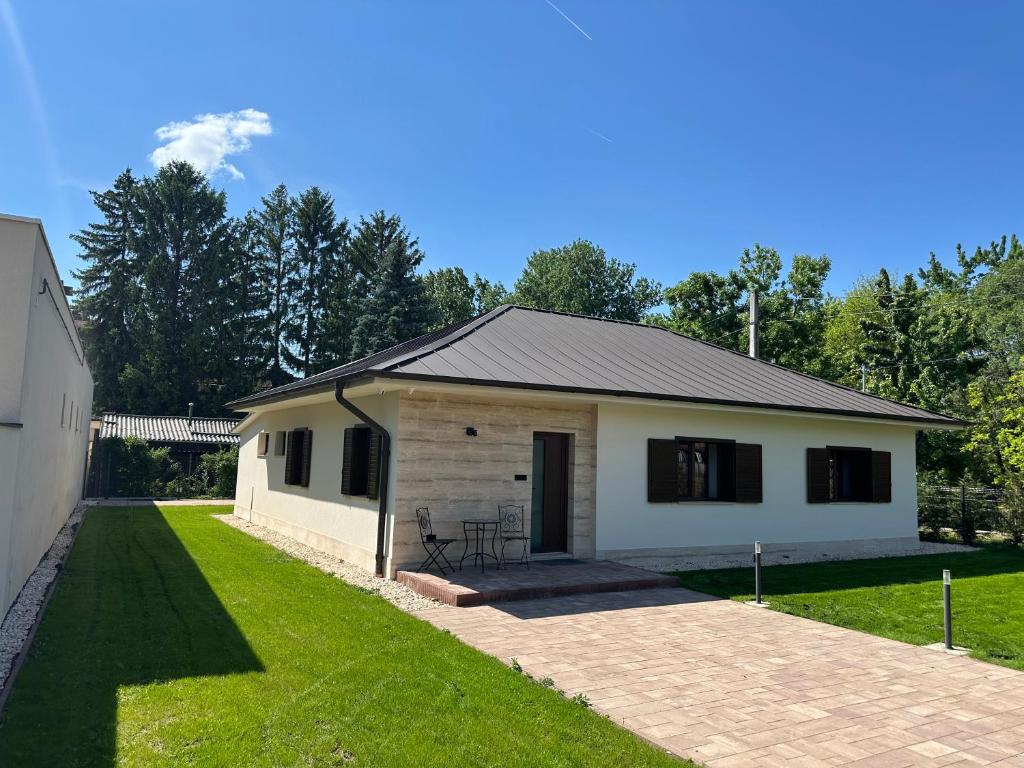 a small white house with a porch and grass at Házikon 2 Apartman in Igricetanya
