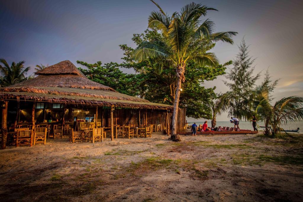 a restaurant on the beach with chairs and a palm tree at The Pier in Thongsala