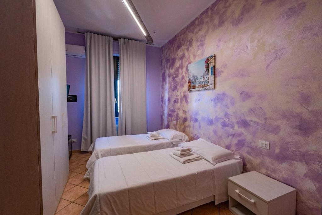 a room with two beds and a purple wall at Locanda San Martino in Collecchio